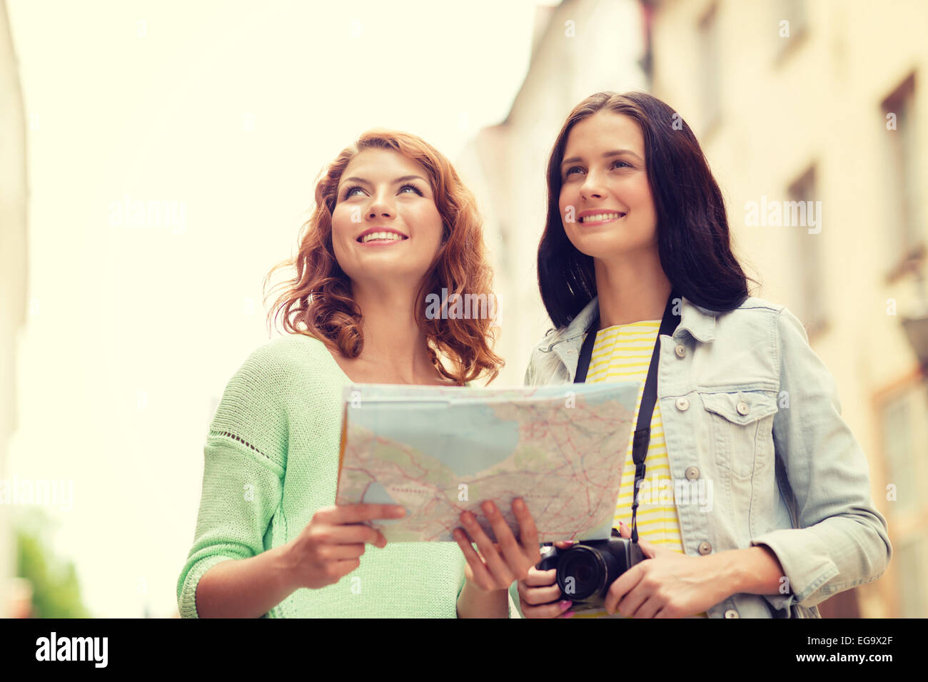 Smiling teenage girls avec la carte et l'appareil photo Banque D'Images