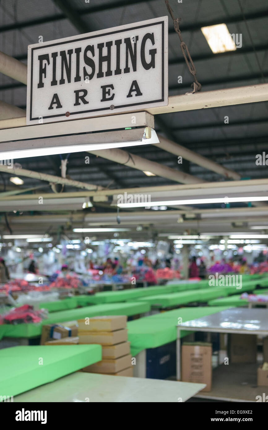 Zone de finition d'usine de confection de vêtements avec les travailleurs de plus en plus floue dans l'arrière-plan Banque D'Images