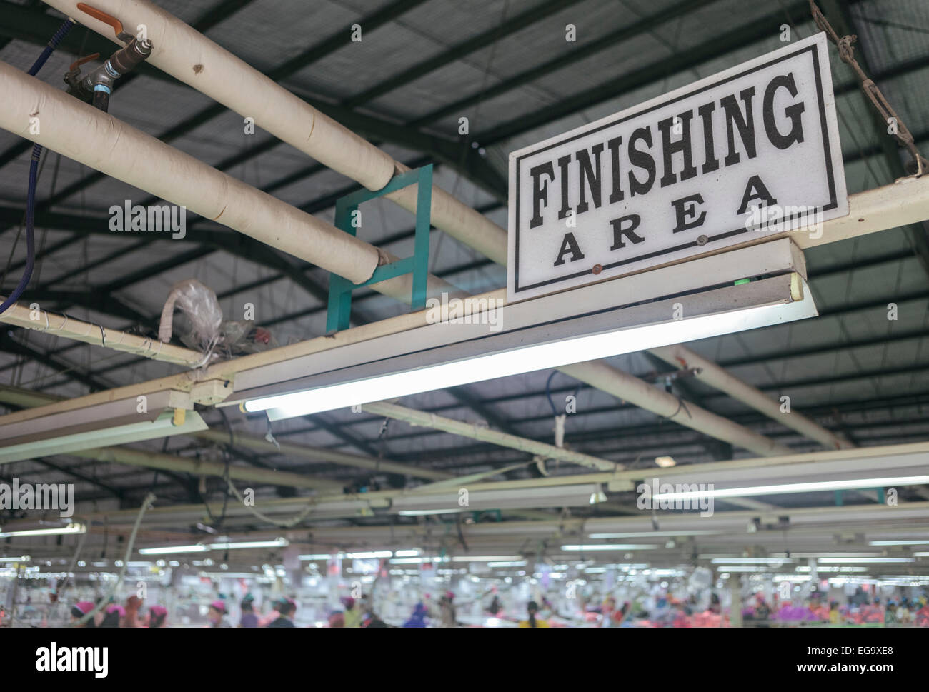 Zone de finition d'usine de confection de vêtements avec les travailleurs de plus en plus floue dans l'arrière-plan Banque D'Images
