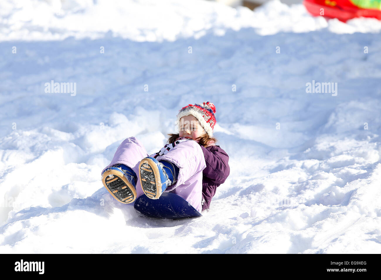 Petite fille joue avec la luge sur la neige en hiver dans les montagnes Banque D'Images