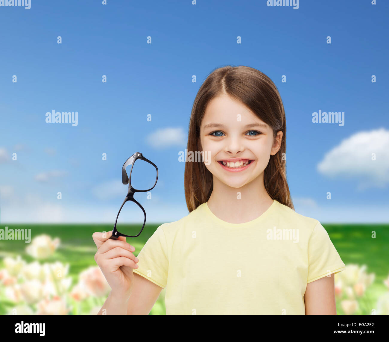 Smiling cute little girl holding lunettes noires Banque D'Images