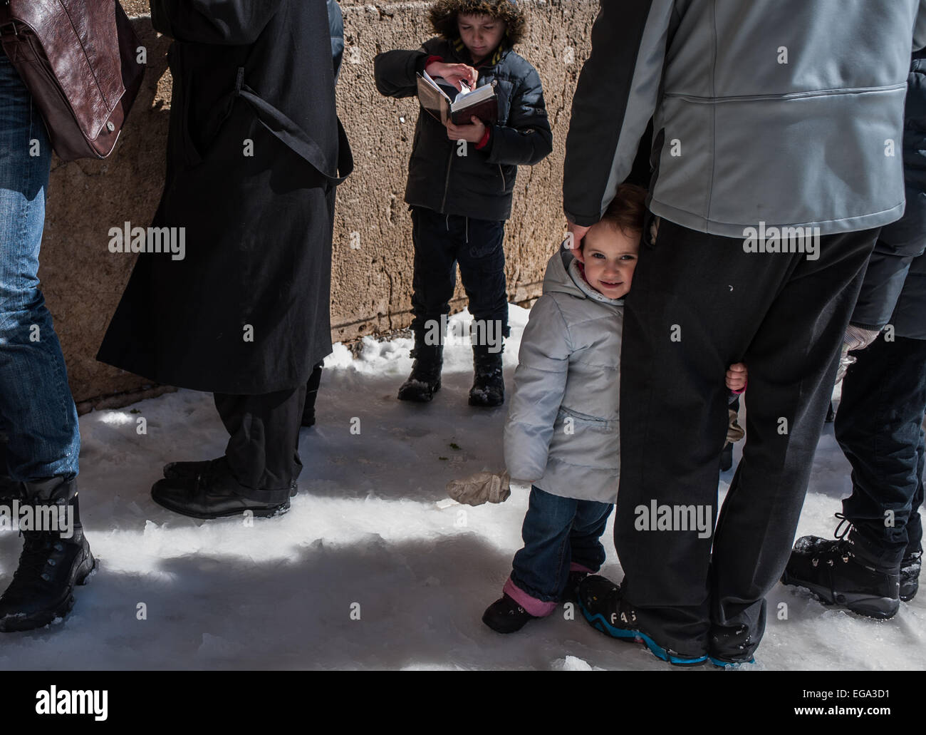 (150220) -- JÉRUSALEM, 20 février, 2015 (Xinhua) -- un enfant épouse père jambe à la neige-couvert Mur Occidental dans la vieille ville de Jérusalem, le 20 février, 2015. Certaines parties d'Israël étaient couvertes de neige tôt le vendredi au milieu d'une tempête d'hiver et de conditions climatiques extrêmes. La neige accumulée jusqu'à des hauteurs inhabituelles d'environ 25 cm à Jérusalem, d'après une déclaration de la municipalité. La voirie à Jérusalem ont été fermées et les résidents de la ville ont été priés de ne pas se déplacer inutilement. La municipalité a dit 250 chasse-neige ont été exploités dans le but de garder les principales routes de la ville menant à Banque D'Images