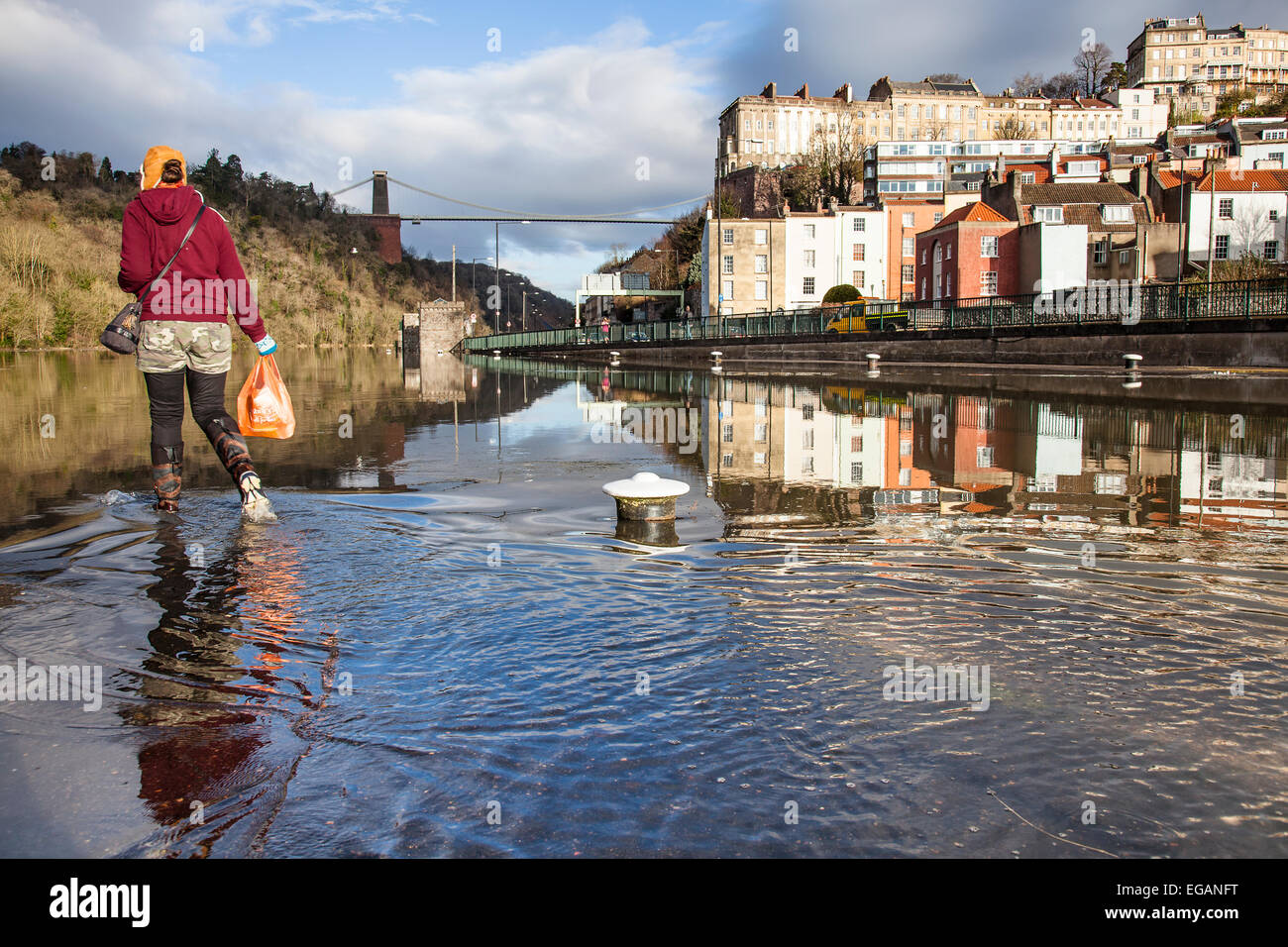Un filtre la femme à l'eau d'inondation du bassin de Cumberland à Bristol lors d'une marée de vive-eau. Pont suspendu de Clifton est à l'arrière-plan. 14,7 mètres de la marée haute à 08,52 Bristol, Royaume-Uni. 21 Février, 2015. Credit : Redorbital Photography/Alamy Live News Banque D'Images