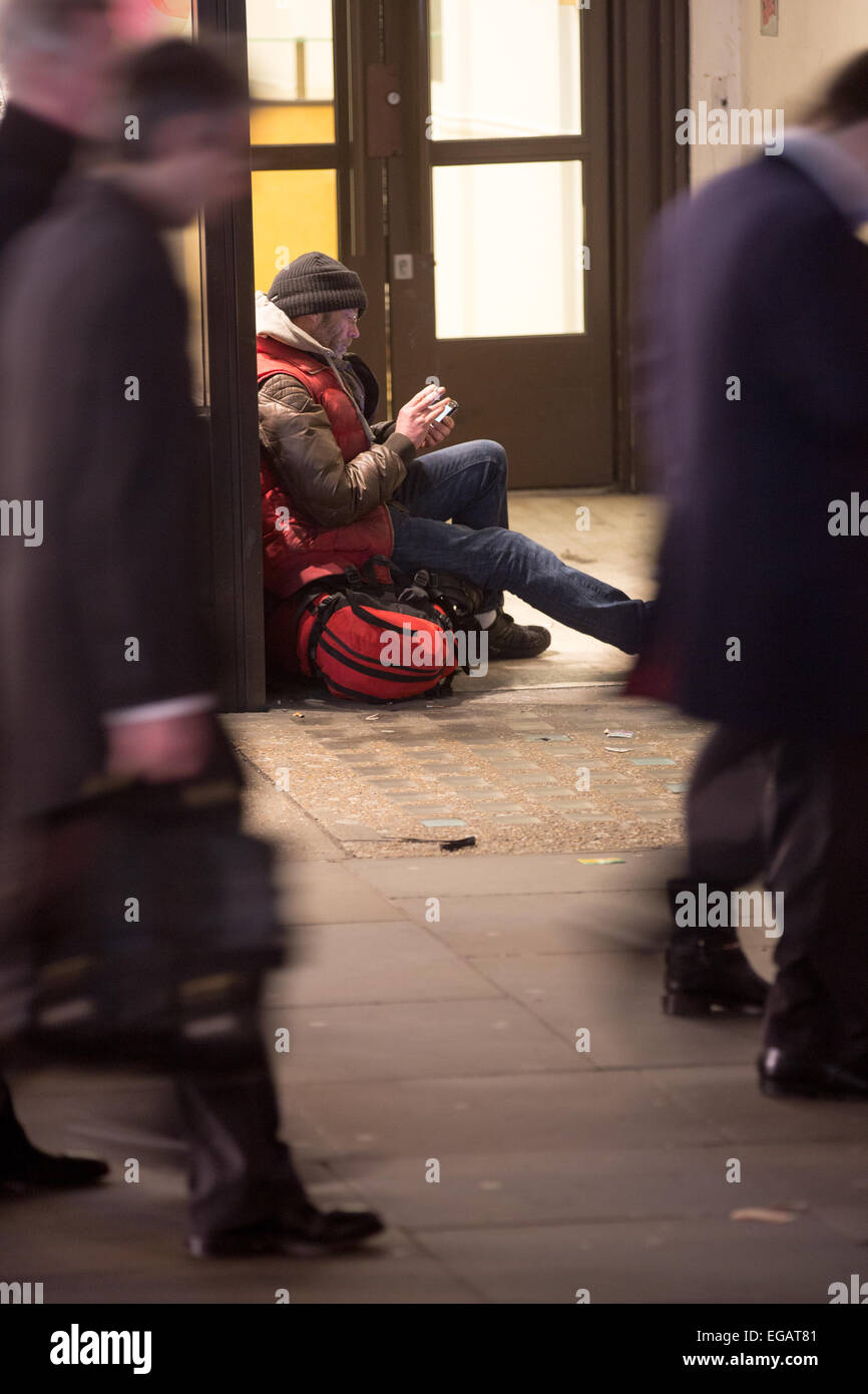 Un homme qui regarde son portable, assis dans une embrasure sur Regent's Street, le centre de Londres à l'heure de pointe. Banque D'Images