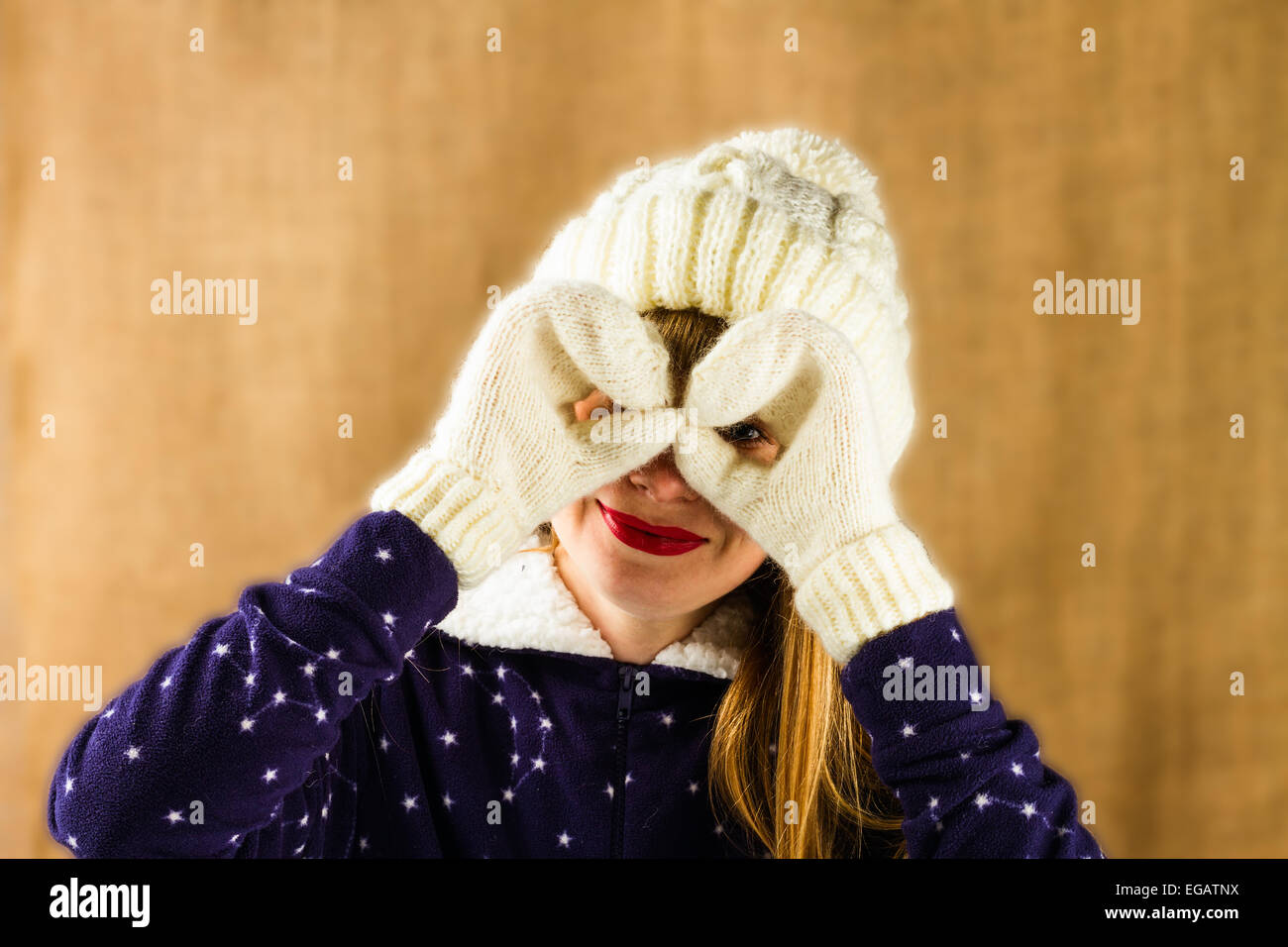 Jeune fille dans un capuchon blanc et tricoté des mitaines sur fond brun Banque D'Images