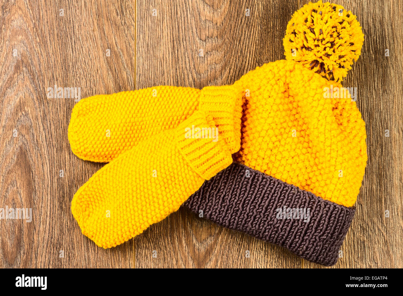 Tricoter des mitaines et chapeau jaune sur fond de bois Banque D'Images