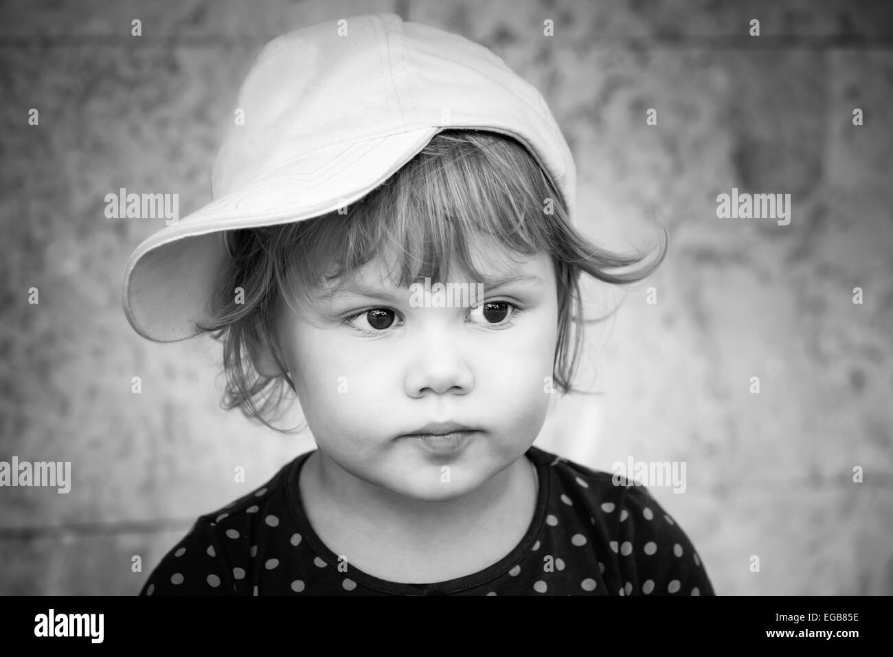 Le noir et blanc closeup portrait of Caucasian baby girl grave en baseball cap Banque D'Images