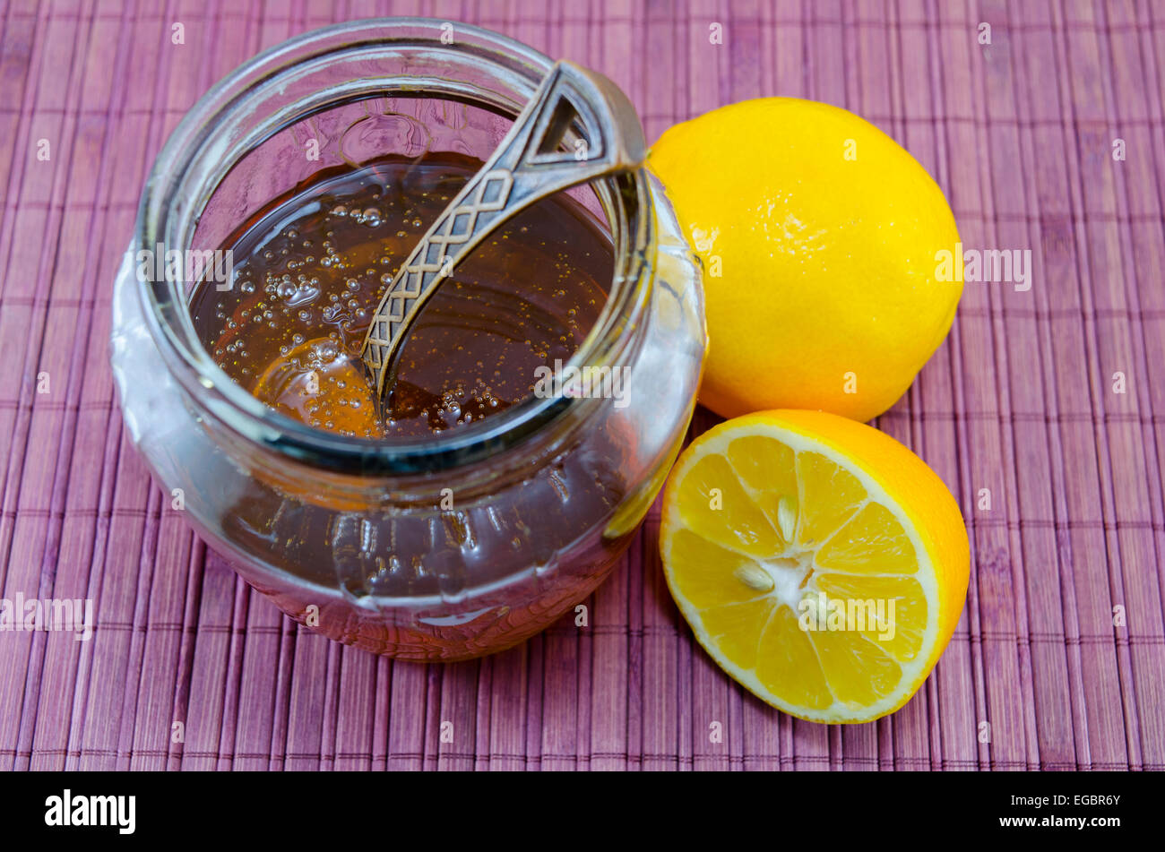 Les noix et miel citron sur une table sur une nappe de bambou rose Banque D'Images