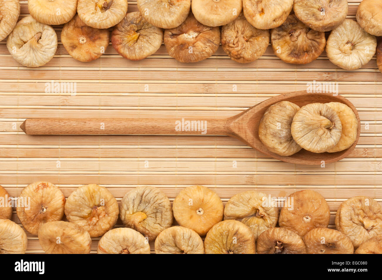 Cuillère en bois avec les figues séchées couché sur le tapis de bambou Banque D'Images