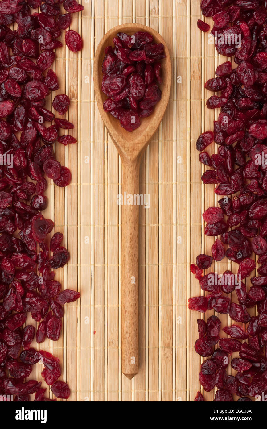 Cuillère en bois avec des canneberges séchées et couché sur le tapis de bambou Banque D'Images