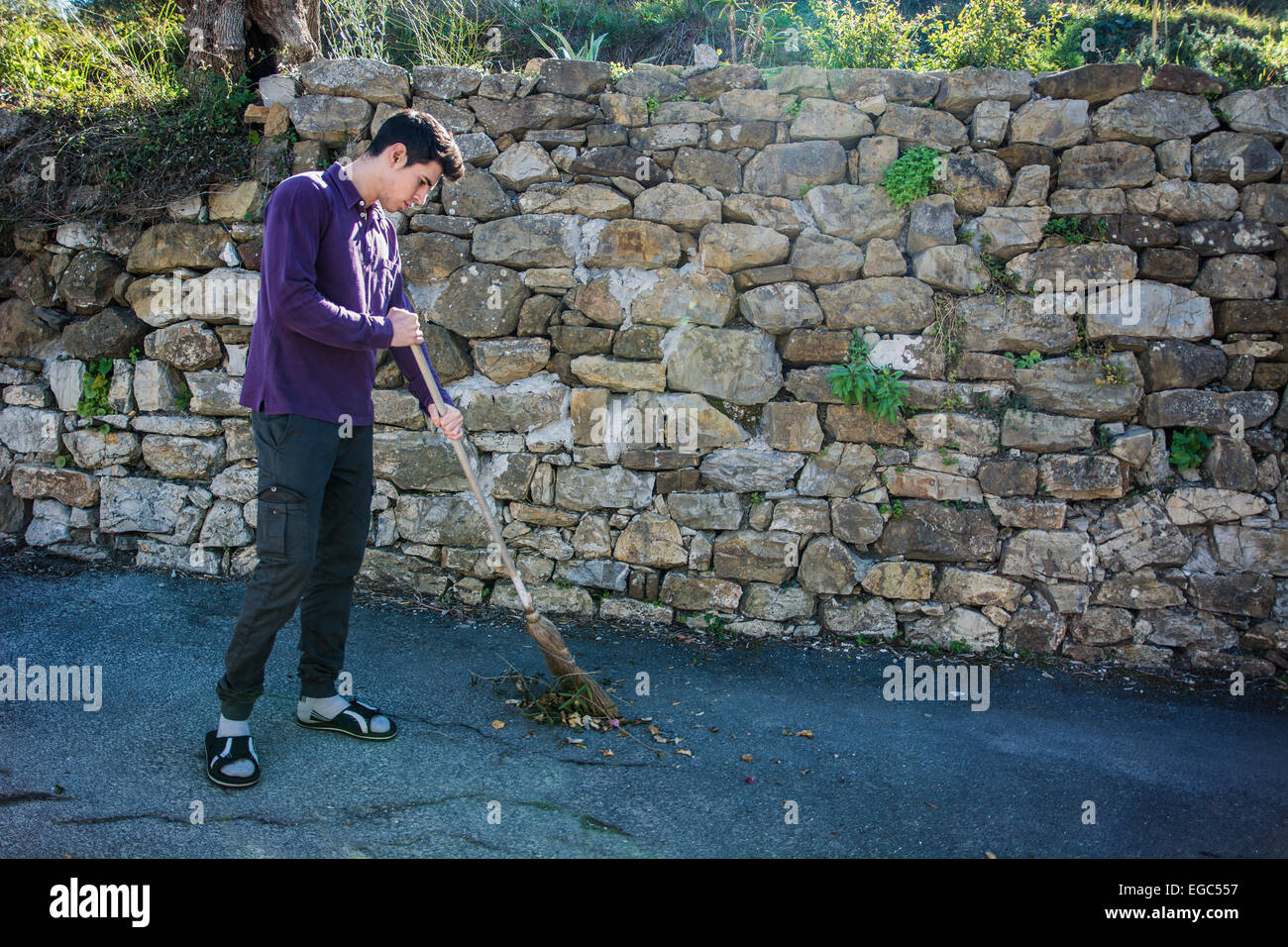 Jeune homme balayer balai avec le feuillage en plein air Banque D'Images