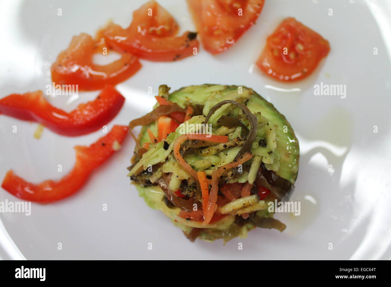 Fraîche appétissante collation cook facile laïcs d'avocat dans une assiette décorée avec des tranches de tomate et piment pâte Banque D'Images