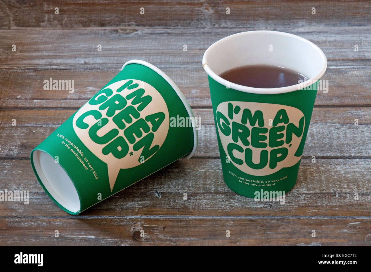 Je suis un bol vert imprimé sur l'avant de 2 100 % compostable tasse en carton qui est genre à l'environnement. Deux sur un plateau en bois Banque D'Images
