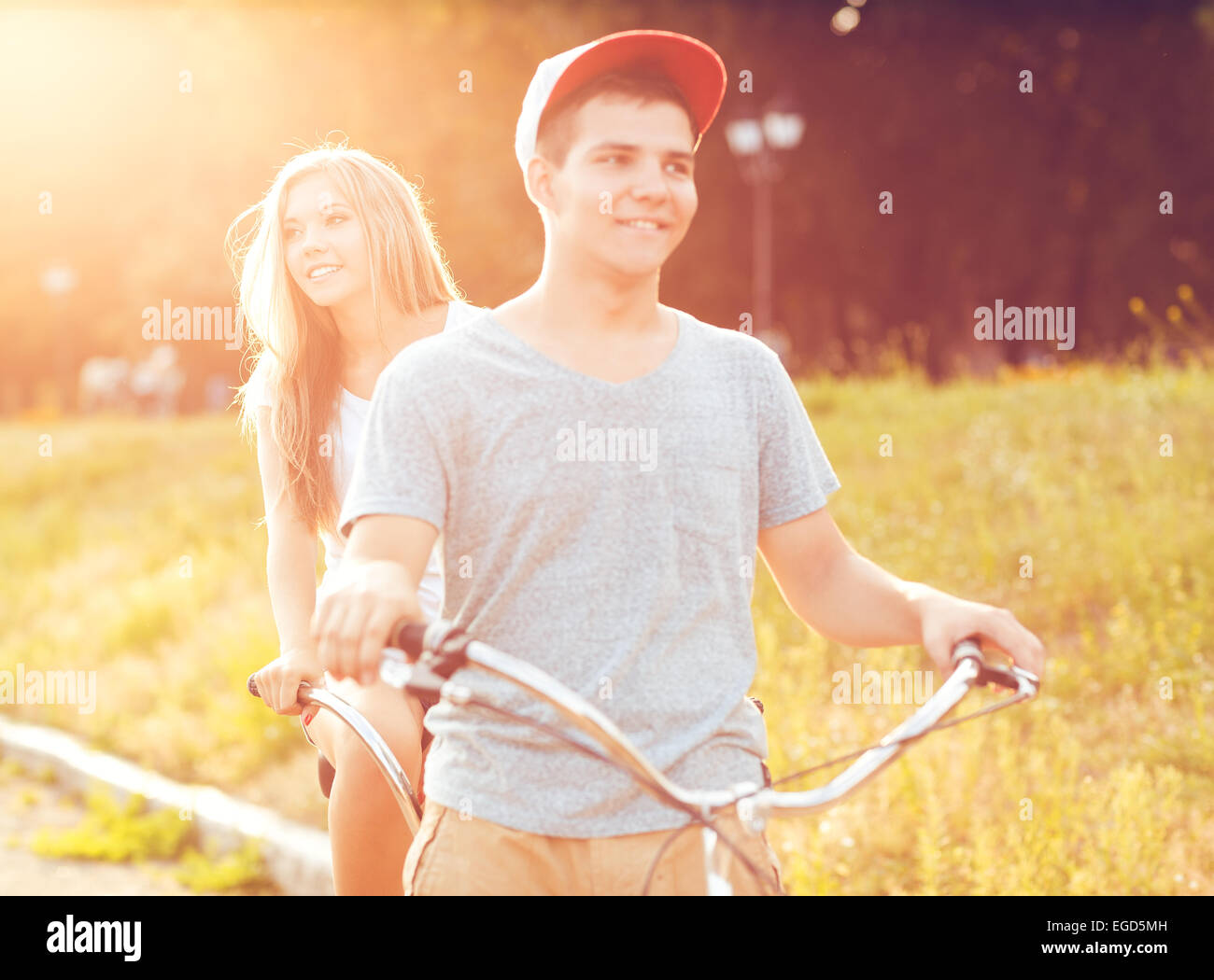 Couple heureux - jeune homme et femme de rouler à vélo dans le parc à l'extérieur Banque D'Images