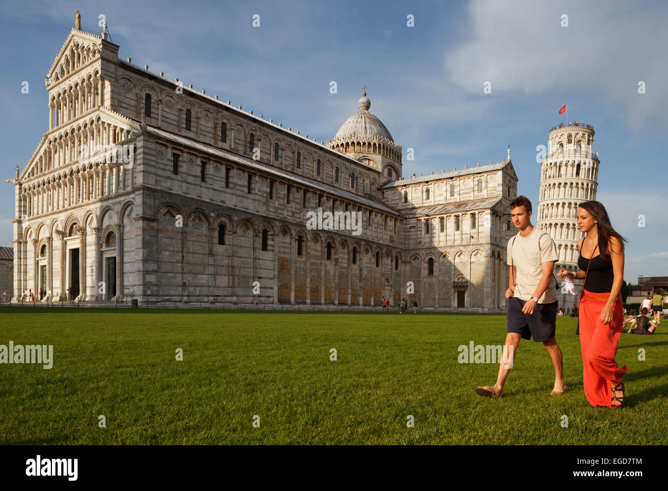 Couple en train de marcher dans l'herbe en face de la cathédrale, la cathédrale, le campanile, clocher, Torre Pendente, tour de Pise, la Piazza dei Miracoli (Place des Miracles, la Piazza del Duomo, la place de la cathédrale, l'UNESCO World Heritage Site, Pise, Toscane, Italie, Europe Banque D'Images