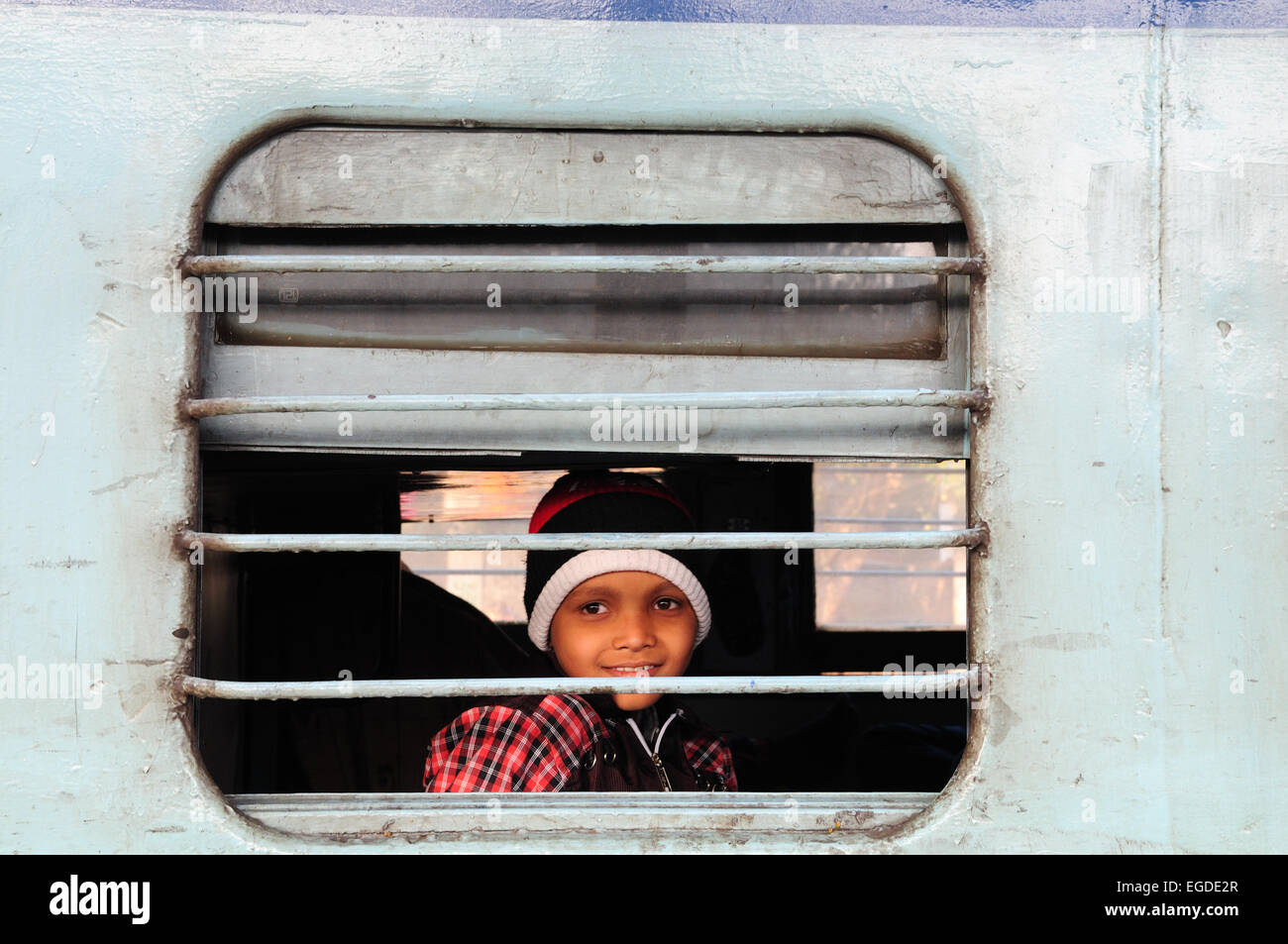 Souriante jeune jeune Indien à la recherche à travers les barreaux d'une fenêtre de train gare de New Delhi Inde Banque D'Images