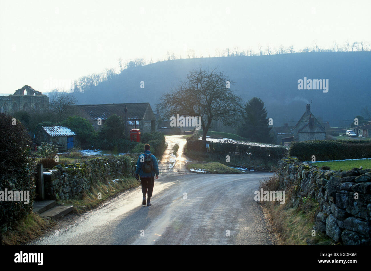 Le dirigeant d'une scène d'hiver avec walker, Rievaulx village, North Yorkshire, UK Banque D'Images