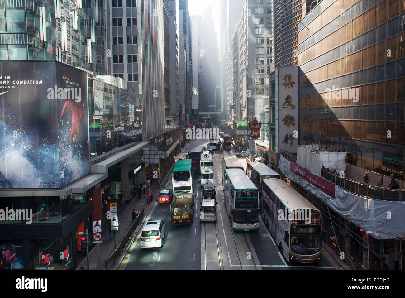 Des Voeux Road et de trafic dans le soleil du matin dans le centre de district. Les bus, trams et voitures amène les gens à travailler tôt le matin. Banque D'Images