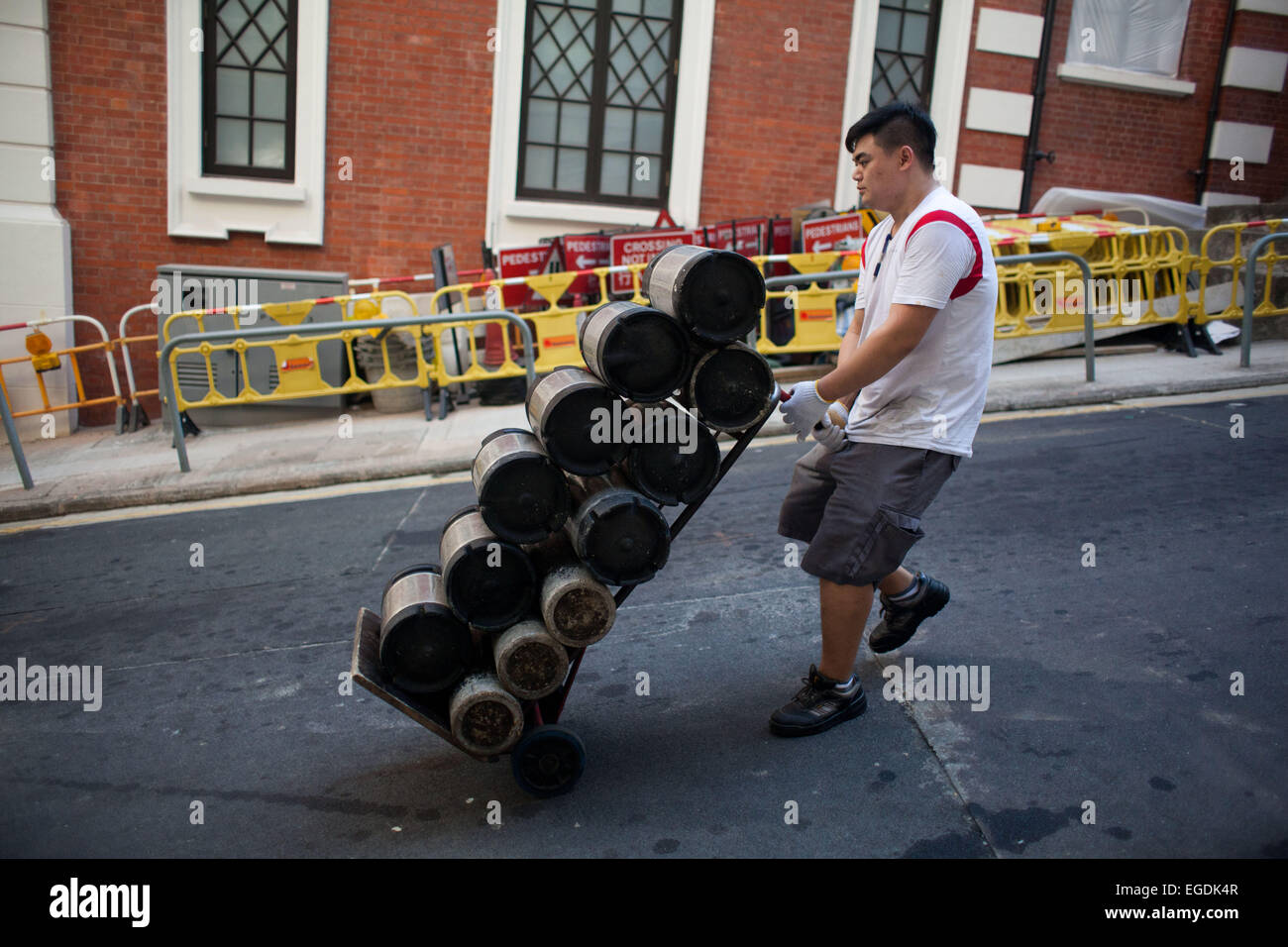 Un livreur roues barils de bière en bas de la colline au milieu de niveaux sur l'île de Hong Kong. Banque D'Images