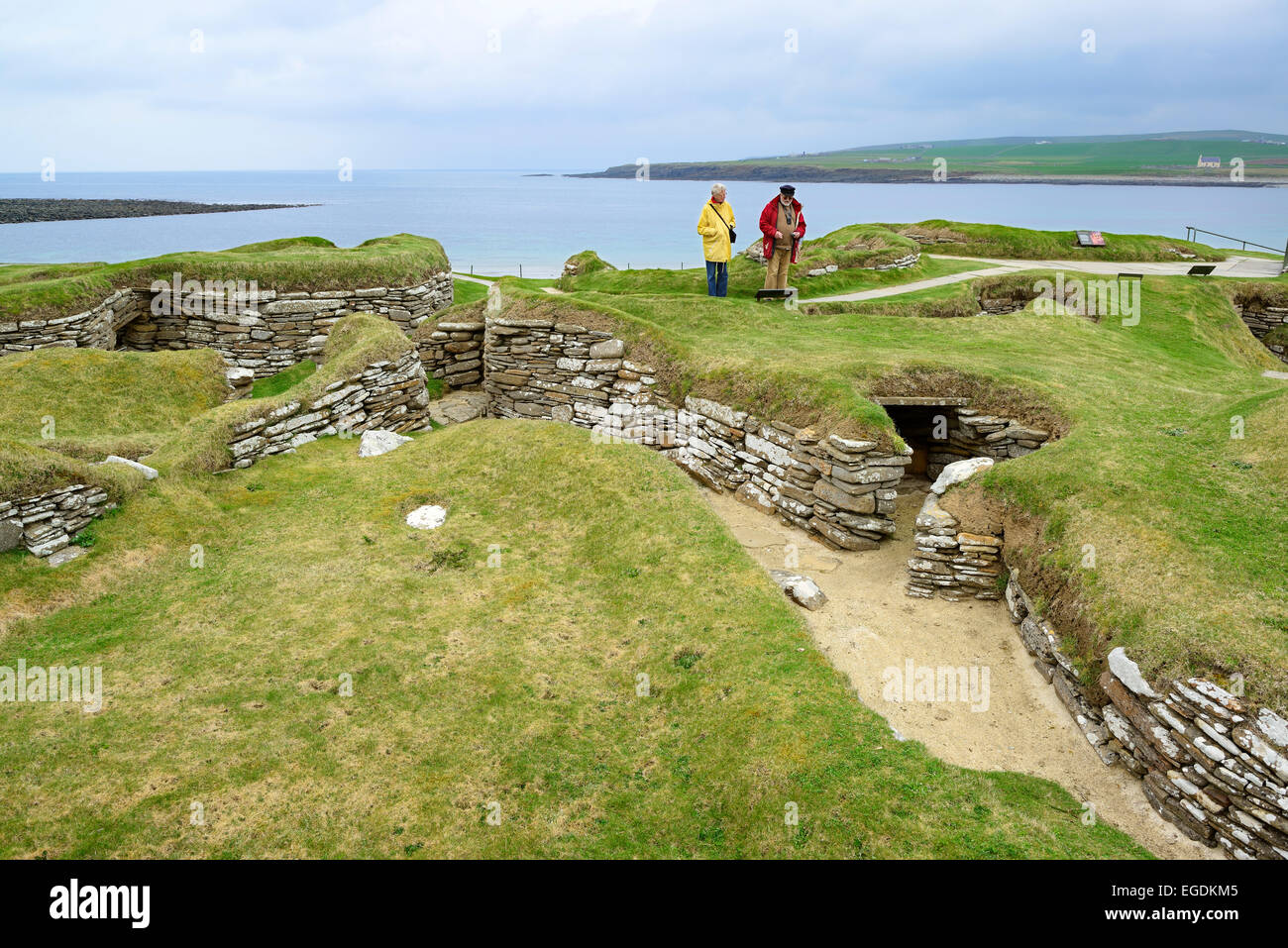 Deux touristes se rendant sur le site néolithique Skara Brae, Skara Brae, Site du patrimoine mondial de l'UNESCO Le Coeur néolithique des Orcades, îles Orcades, Ecosse, Grande-Bretagne, Royaume-Uni Banque D'Images
