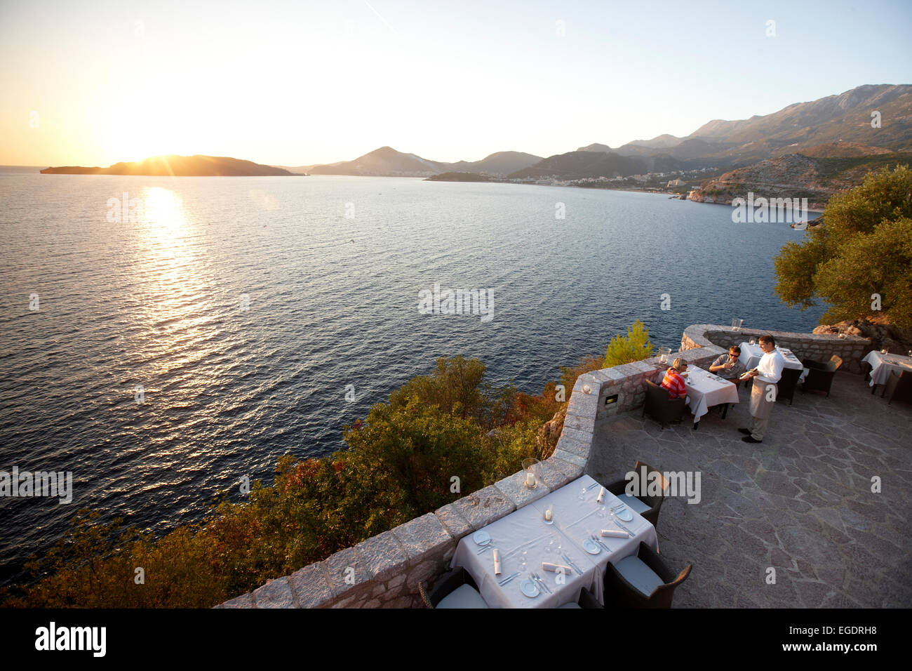 Couple en train de dîner sur la terrasse d'un restaurant, vue sur la baie de Budva, Aman Sveti Stefan, Sveti Stefan, Budva, Monténégro Banque D'Images