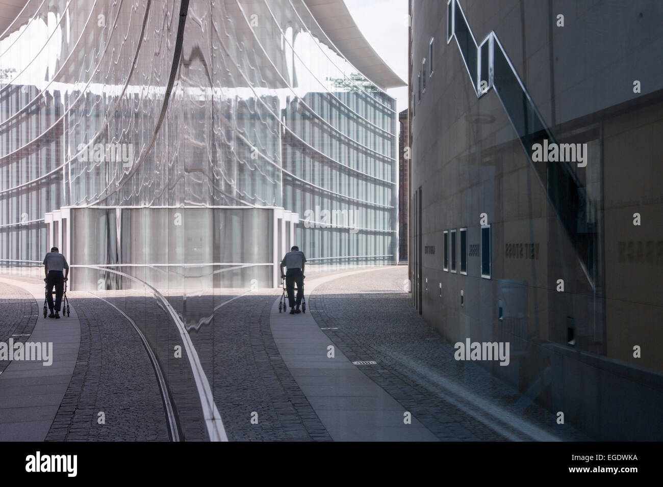 La réflexion de l'homme avec walker dans la fenêtre du musée d'art moderne, le Neues Museum, Nuremberg, Franconia, Bavaria, Germany Banque D'Images