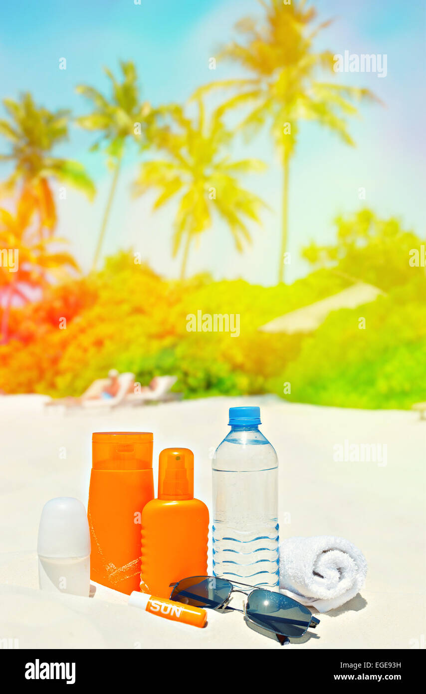 Crème solaire et lunettes de soleil sur fond de palm beach. Paysage Tropical. Retro style tonique photo avec pénétration de la lumière Banque D'Images