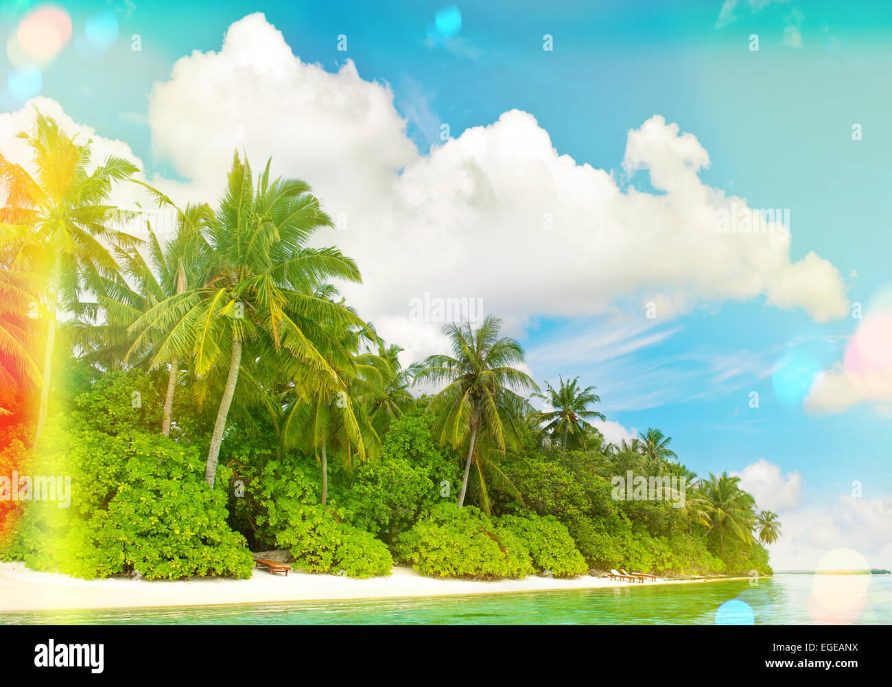 La plage de sable tropicale avec palmiers et ciel bleu ensoleillé. Tons style vintage photo avec la lumière des torches et des fuites Banque D'Images