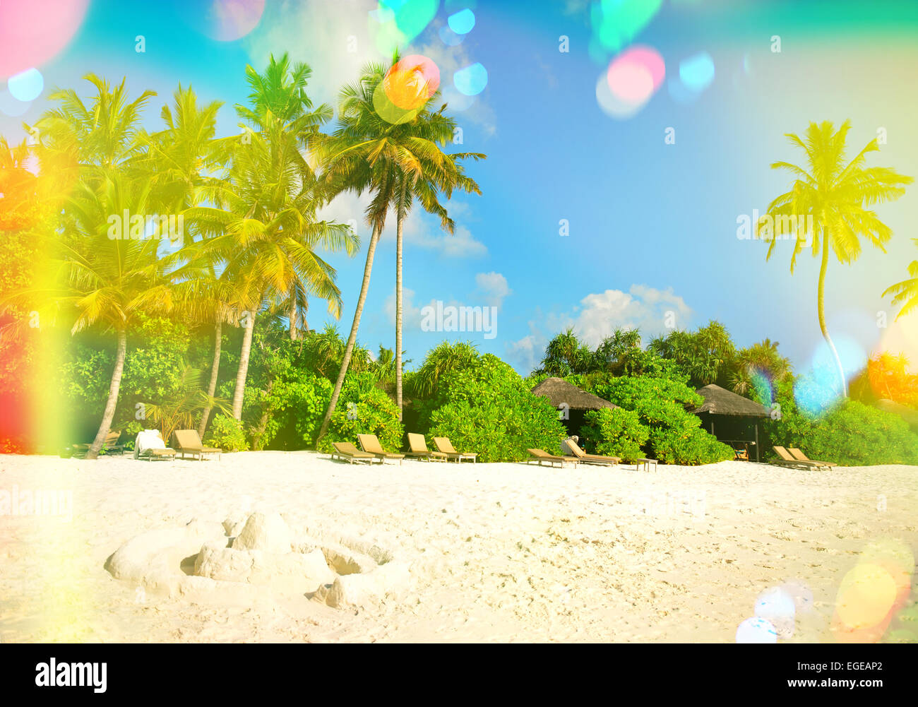 La plage de sable tropicale avec palmiers et ciel bleu ensoleillé. Tons style vintage photo avec pénétration de la lumière et reflets de l'objectif Banque D'Images