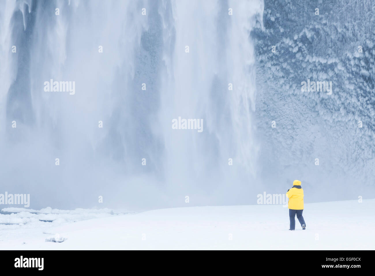 Touriste dans la région de Yellow Jacket à Skogafoss chute d'eau gelée Skogar Islande Islande Europe du Sud Banque D'Images