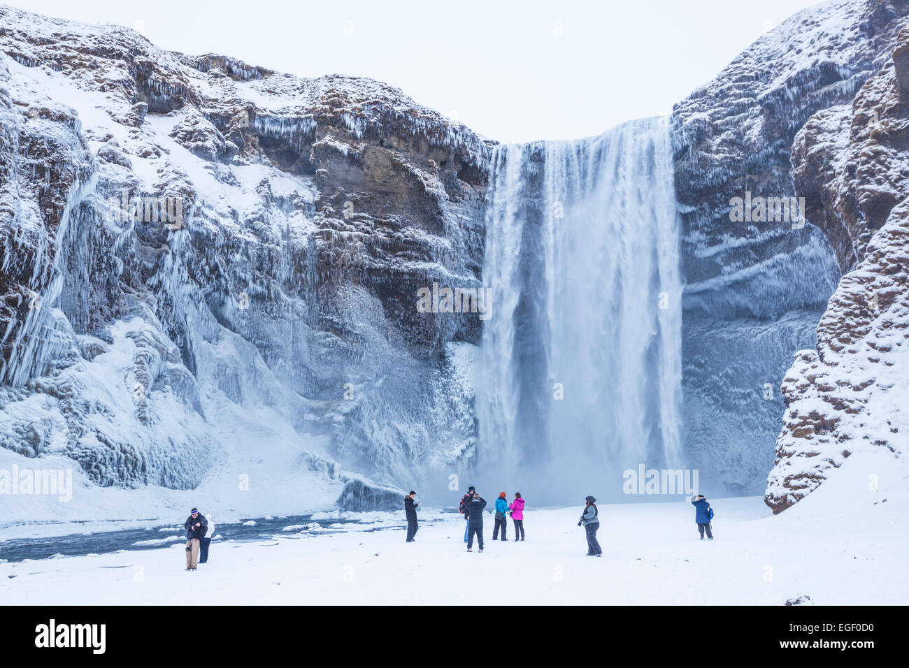 Les touristes visitant Skogafoss chute d'eau gelée Skogar le Sud de l'Islande Islande Europe Banque D'Images