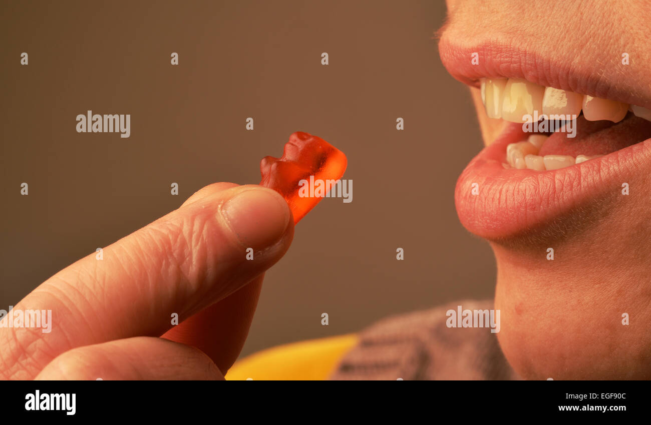 Image symbolique sur le sucre dans les aliments : Woman eating gummy bears. Banque D'Images