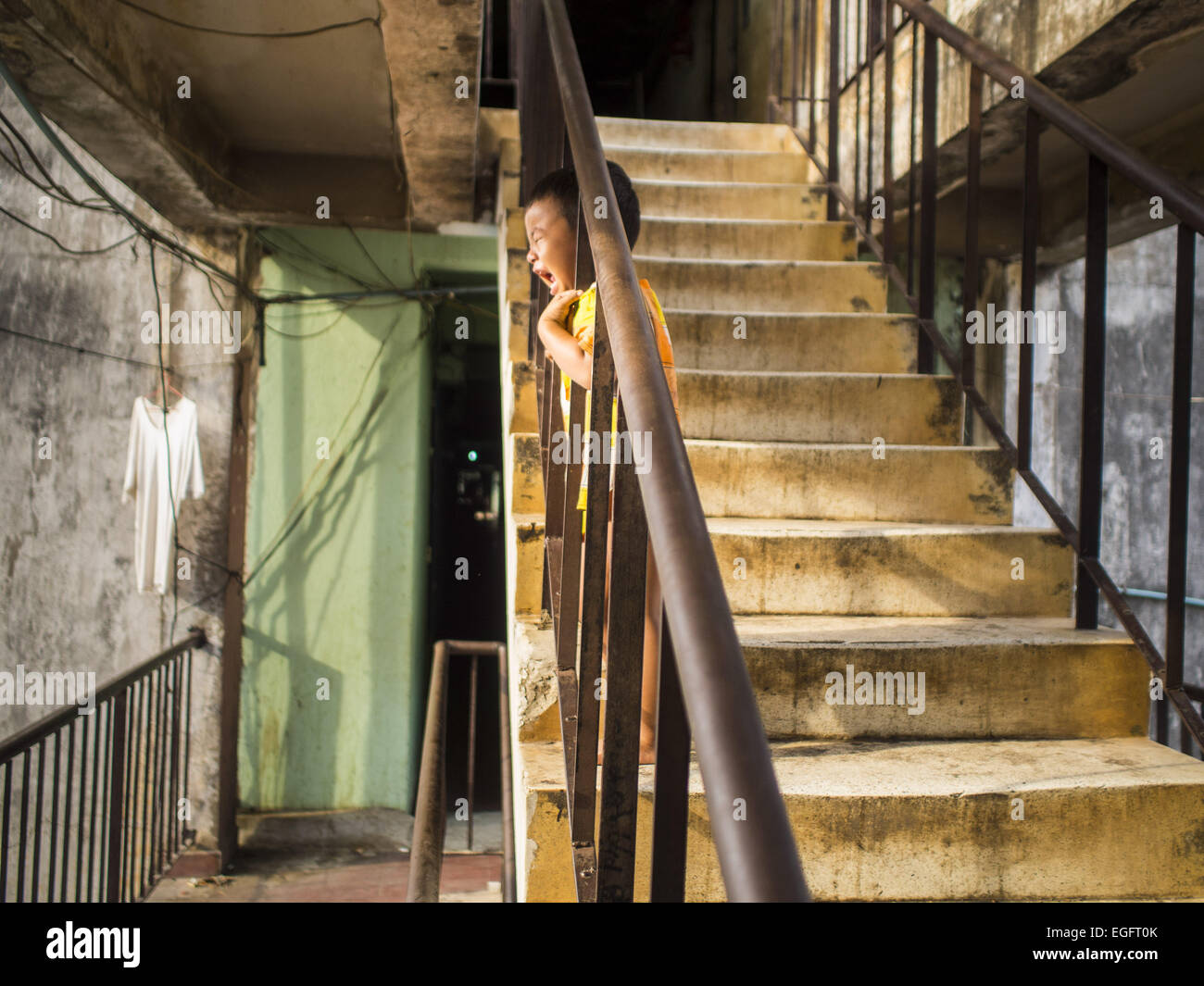 Phnom Penh, Phnom Penh, Cambodge. Feb 24, 2015. Un enfant crie dans un escalier dans le bâtiment blanc. Le bâtiment blanc, le premier immeuble d'appartements modernes à Phnom Penh, à l'origine, avait 468 appartements, et a été ouvert au début des années 1960. Le projet a été supervisé par Vann Molyvann, le premier architecte cambodgien fait ses études en France. Le bâtiment a été abandonnée au cours de l'occupation des Khmers rouges. Après les Khmers rouges ont été chassés de Phnom Penh en 1979, des artistes et des danseurs a déménagé dans le bâtiment blanc. © ZUMA Press, Inc./Alamy Live News Banque D'Images