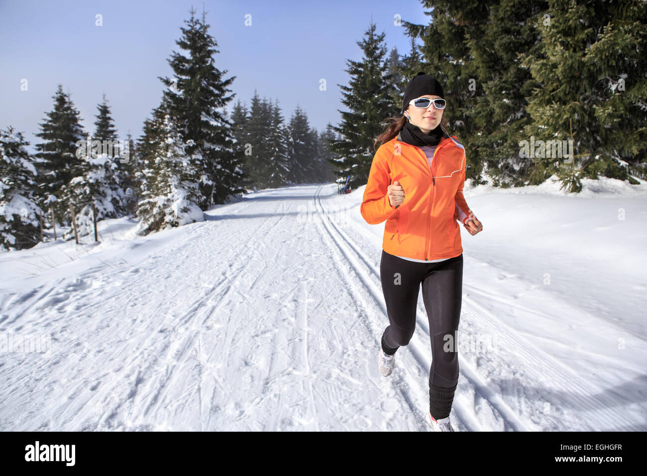 Une jeune femme le jogging dans la forêt d'hiver Banque D'Images
