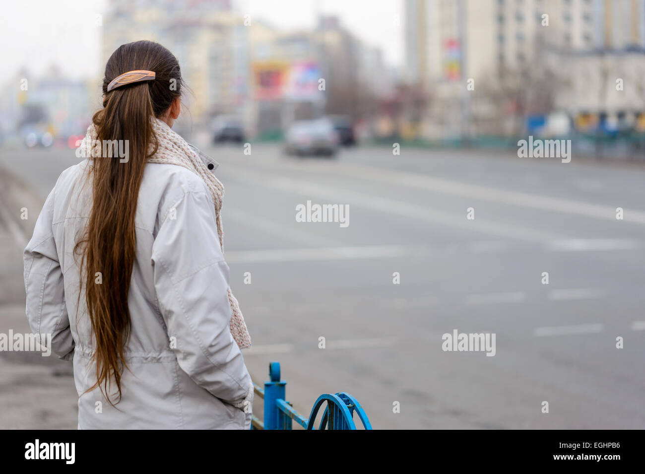 Une femme avec une queue d'attente, ou de regarder, près de la rue avec des voitures dans la ville Banque D'Images