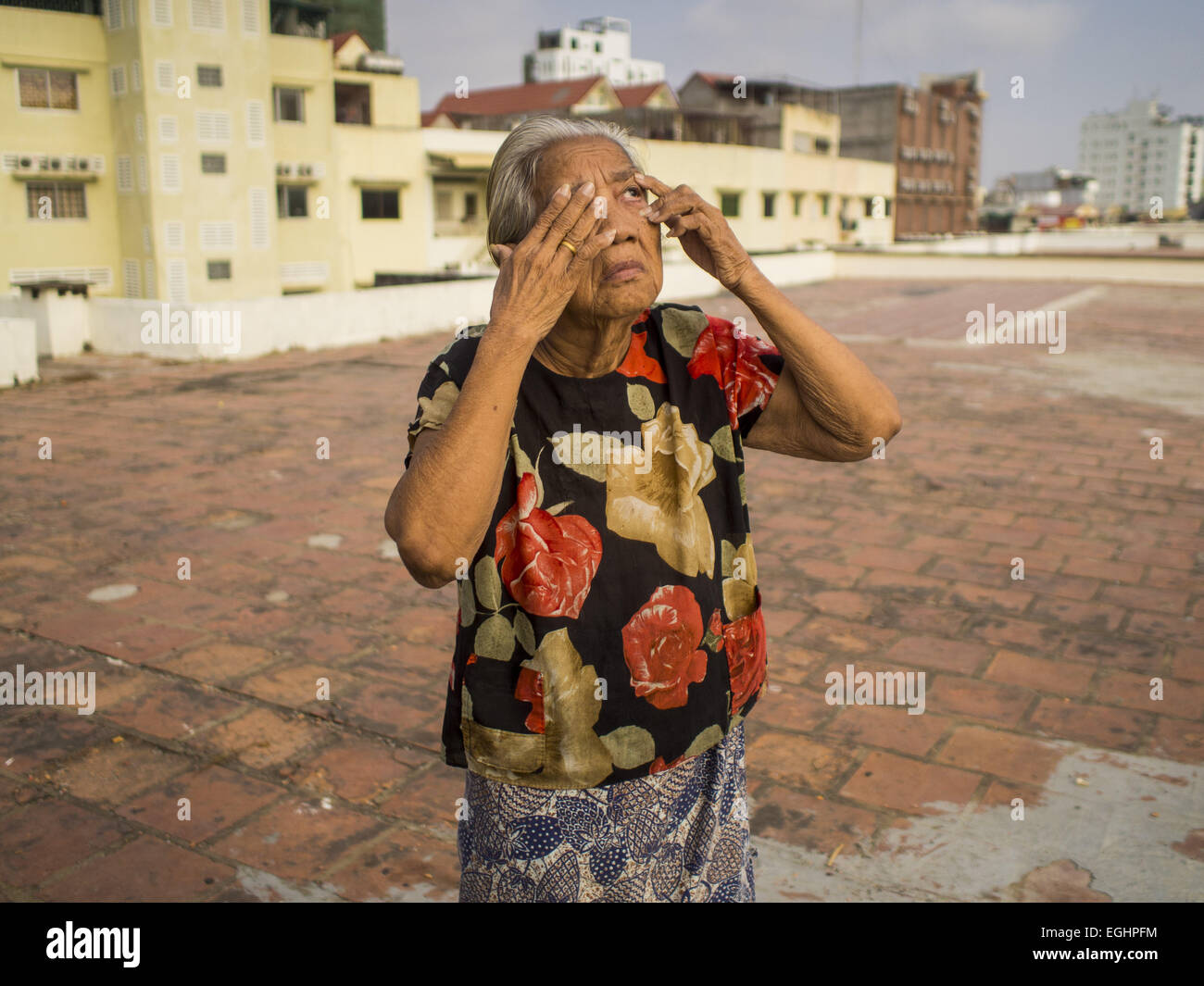 Phnom Penh, Phnom Penh, Cambodge. Feb 25, 2015. Une femme termine son exercice de routine du matin sur le toit de l'édifice blanc à Phnom Penh. Le bâtiment blanc, le premier immeuble d'appartements modernes à Phnom Penh, à l'origine, avait 468 appartements, et a été ouvert au début des années 1960. Le projet a été supervisé par Vann Molyvann, le premier architecte cambodgien fait ses études en France. Le bâtiment a été abandonnée au cours de l'occupation des Khmers rouges. Après les Khmers rouges ont été chassés de Phnom Penh en 1979, des artistes et des danseurs a déménagé dans le bâtiment blanc. Maintenant, environ 2 500 personnes, majoritairement urbaine et de travail poo Banque D'Images