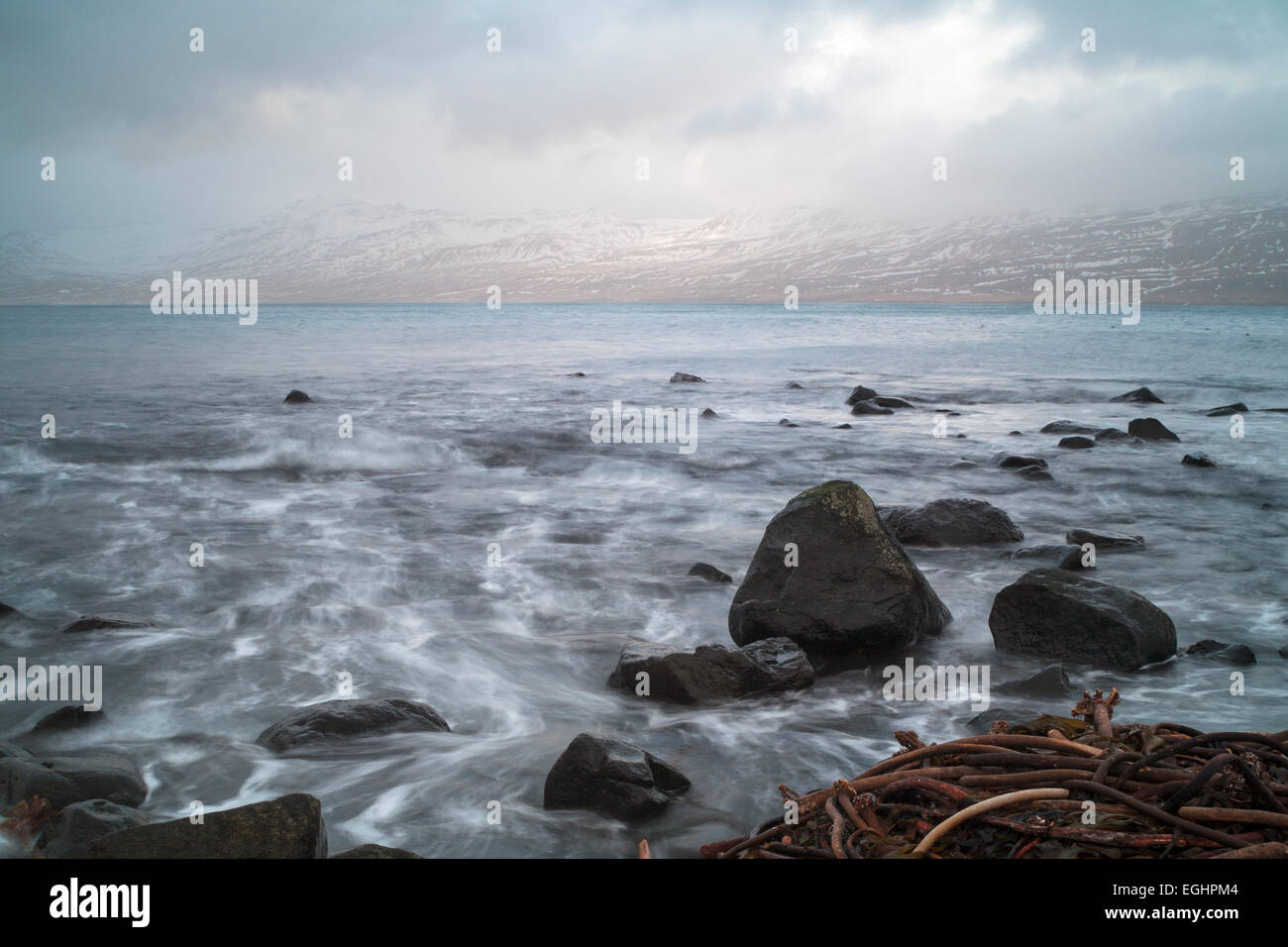 Une longue exposition de vagues déferlaient sur les rochers sur la plage à Hafnarnes Fáskrúðsfjörður, Faskrudsfjordur, est de l'Islande en Février Banque D'Images