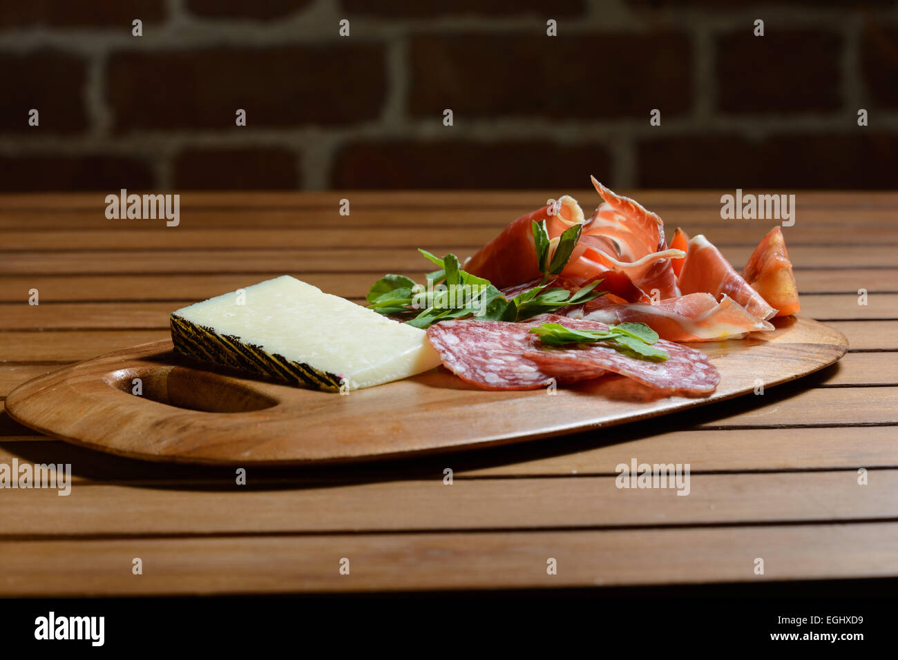 Conseil d'Antipasti Tapas : Jambon Serrano, Salchicon salami, salade de tomates et fromage Manchego décoré de feuilles de pois vert. Banque D'Images