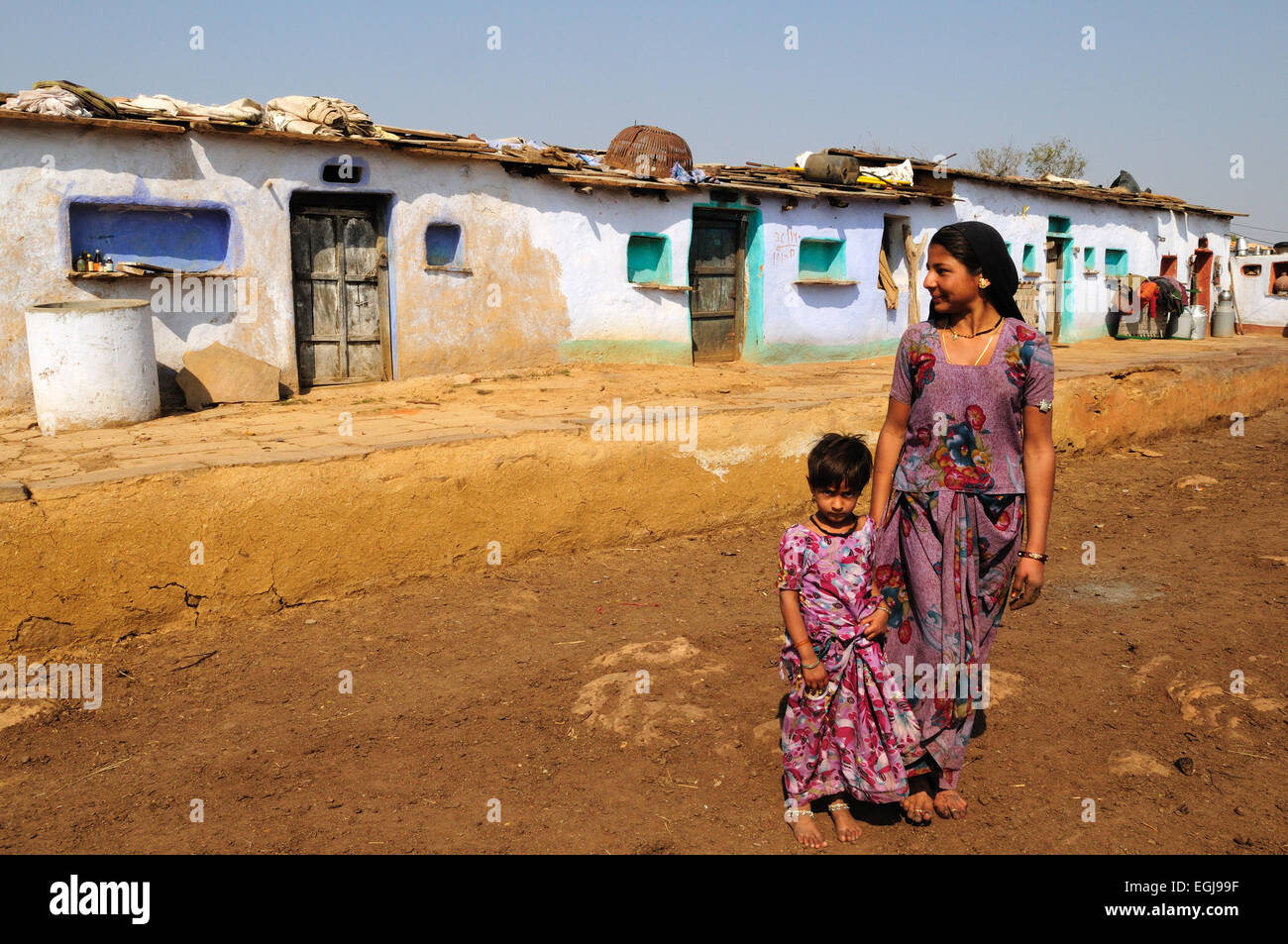 Femme indienne et sa fille debout à l'extérieur des maisons de village tribal Village Kalpi le Rajasthan en Inde Banque D'Images
