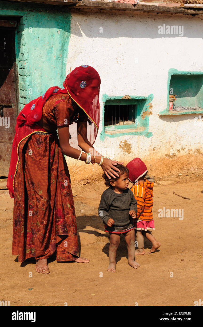 Une femme indienne s'occupe de ses enfants à l'extérieur de leur village tribal Accueil Village Kalpi le Rajasthan en Inde Banque D'Images