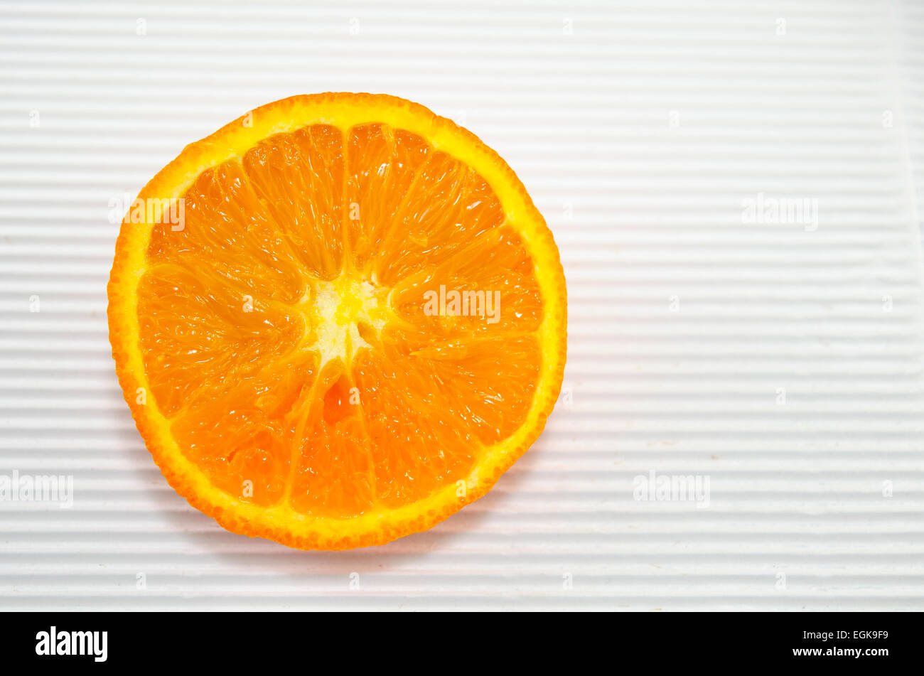 Tranche de juteux de moitié orange sur un carton blanc Banque D'Images
