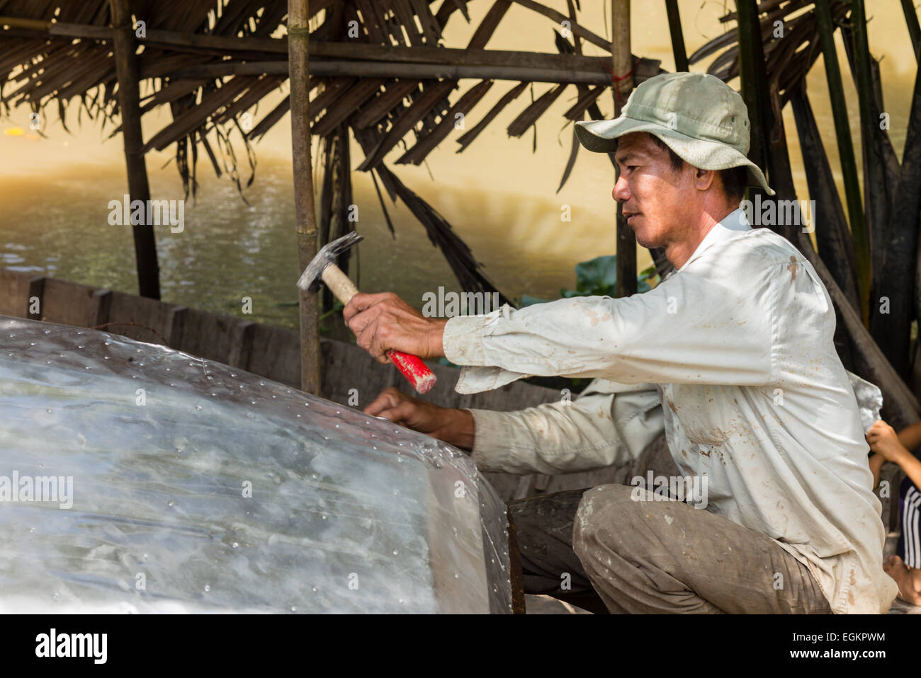 La réparation de pêcheur bateau dans la campagne agricole le long des canaux du Mékong dans le Delta du Mékong du Vietnam. Banque D'Images