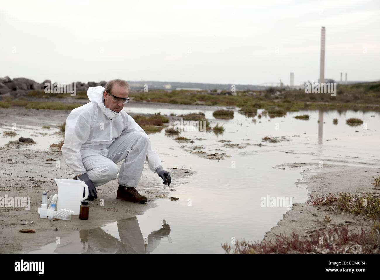 Travailleur dans une combinaison de protection de l'examen de la pollution dans l'eau à l'industrie. Banque D'Images