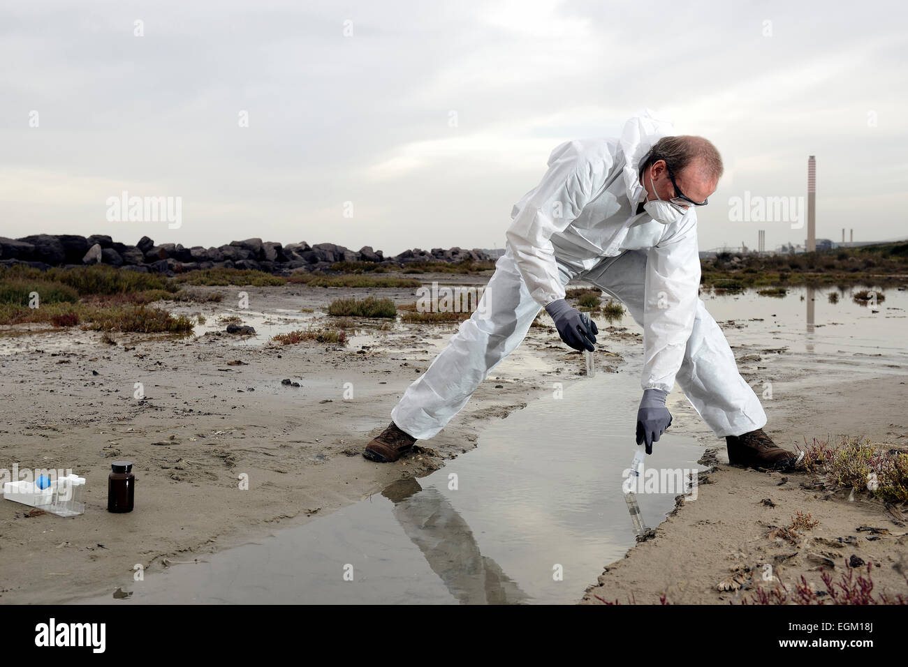 Travailleur dans une combinaison de protection de l'examen de la pollution dans l'eau à l'industrie. Banque D'Images