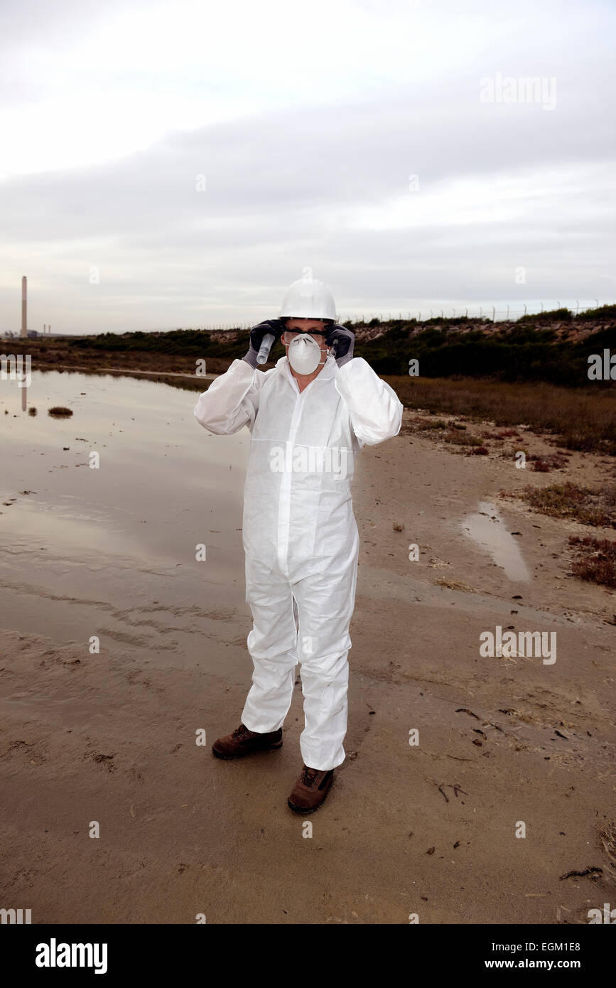 Travailleur dans une combinaison de protection de l'examen de la pollution dans l'eau à l'industrie. Banque D'Images