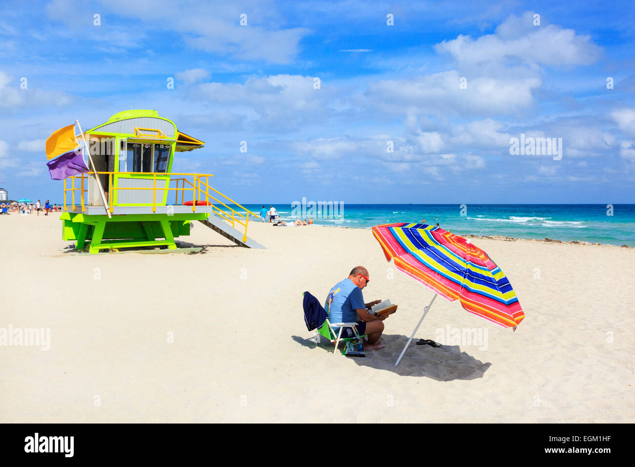 L'homme en train de lire à l'ombre d'un parasol, Miami South Beach, Florida, USA Banque D'Images