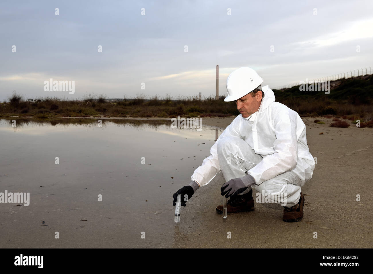 Travailleur dans une combinaison de protection de l'examen de la pollution dans l'eau à l'industrie. Banque D'Images