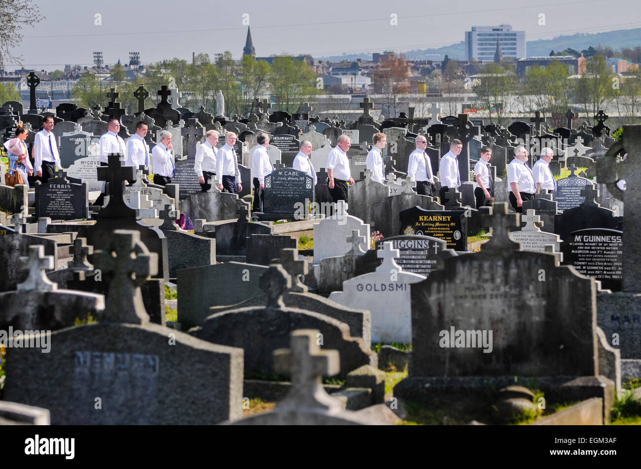 Belfast, Irlande du Nord. 20 Apr 2014 - une ligne d'hommes portant des chemises blanches font leur chemin à travers un cimetière. Banque D'Images