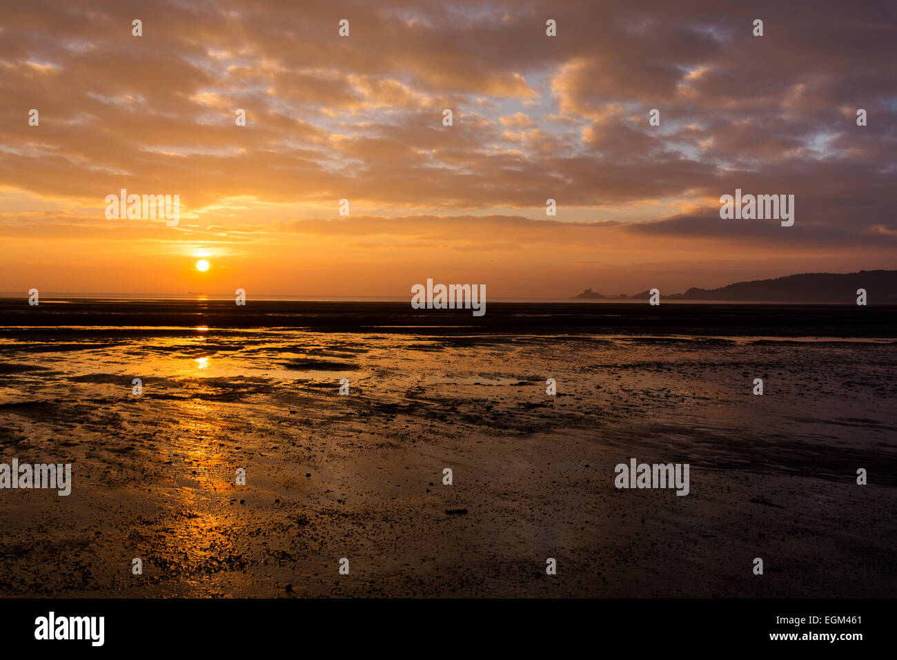 Le soleil se lève sur la mer à côté du phare et lifeboat cabanes dans Mumbles, Galles du Sud, jetant un brillant réflexion sur t Banque D'Images