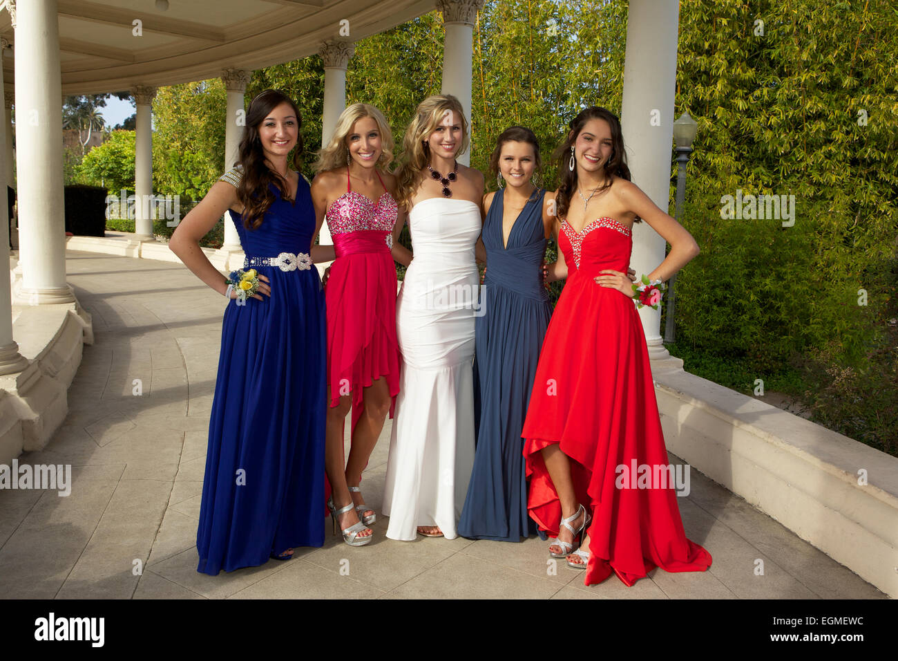 Cinq belles jeunes filles en robe de soirée en souriant et posant pour une photo à l'extérieur Banque D'Images